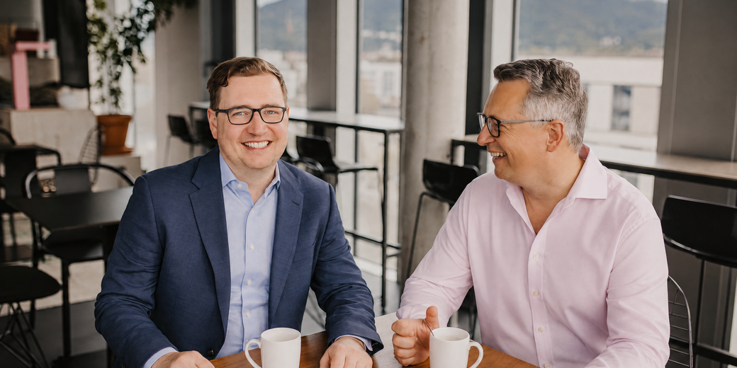 Sebastian Fastner und Sebastian Werner im Gespräch an einem Tisch mit Kaffee
